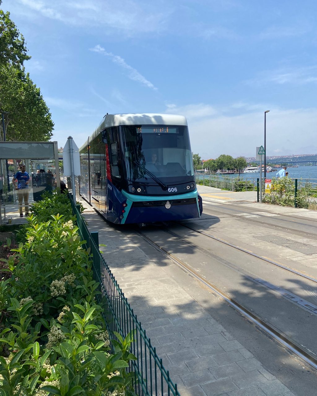 Teal and dark-blue tram running on tracks beside the Golden Horn promenade.