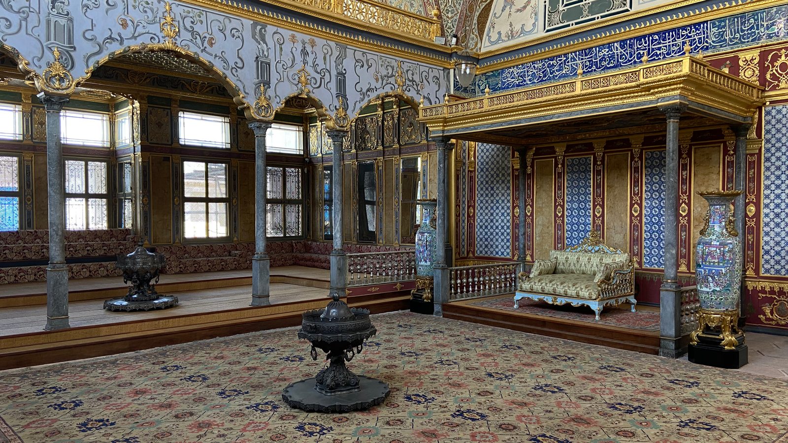 Imperial Hall in Topkapı Palace Harem: gilded canopy over a gold sofa, blue-and-white tiled walls, porcelain vases and cushioned benches